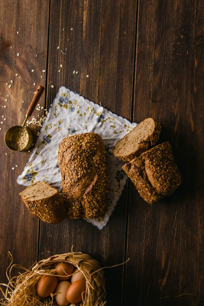 Artisan sliced multigrain bread on a wooden table with eggs and seeds, invoking a rustic vibe.